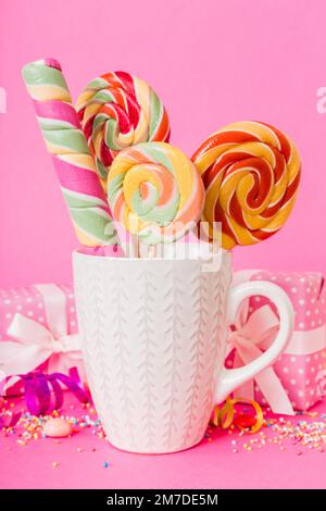 Bonbons colorés dans une tasse sur une table sur fond clair. Grands sucettes tournantes. Concept créatif d'un pot rempli de délicieux bonbons de la Banque D'Images