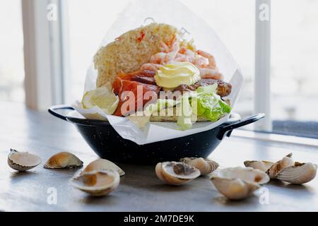 Plat avec hamburger avec saumon et crevettes sur table décorée avec coquillages, îles Lofoten, Norvège Banque D'Images