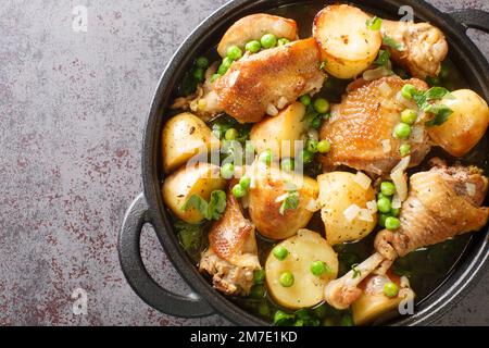 Cuisine italienne américaine poulet Vesuvio une poêle avec pommes de terre, ail, pois verts à proximité de la poêle noire sur la table. Vue horizontale du dessus à partir d'un Banque D'Images