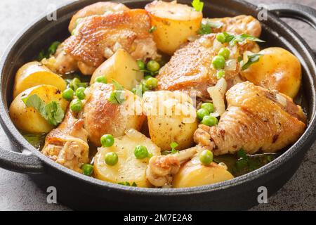 Cuisine italienne américaine poulet Vesuvio une poêle avec pommes de terre, ail, pois verts à proximité de la poêle noire sur la table. Horizontale Banque D'Images