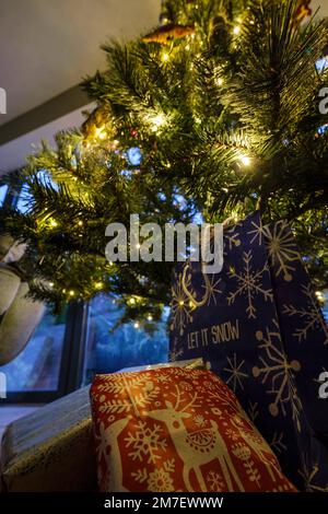 Des cadeaux de Noël enveloppé dans du papier d'emballage coloré sous un arbre de Noël de la famille. Banque D'Images