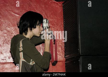 Une fille photographie LES CHIOTS CHAUDS lors d'un concert au Barfly à Cardiff, février 10 2004 avec un appareil photo compact des années 90 contre un mur rouge du club. Photographie : ROB WATKINS Banque D'Images