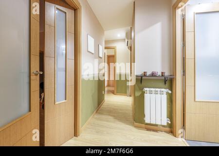 Entrée d'une maison avec accès à plusieurs pièces par des portes en chêne et radiateur en aluminium blanc Banque D'Images