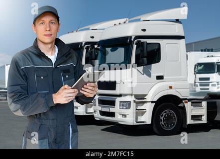 Manager avec une tablette numérique à côté des camions. Gestion de parc Banque D'Images