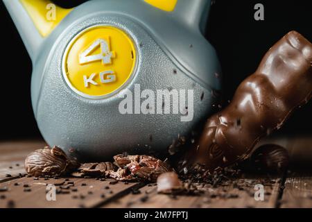 Lourde kettlebell écrasant les œufs de Pâques au chocolat et le lapin sur une table en bois. Entraînement sportif et entraînement sportif. Concept de régime alimentaire sain. Banque D'Images