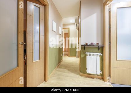 Entrée d'une maison avec accès à plusieurs pièces par des portes en chêne et radiateur en aluminium blanc Banque D'Images