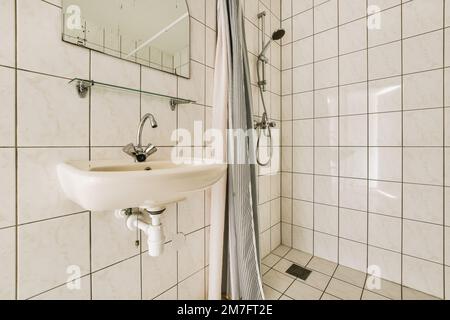 une salle de bains avec un lavabo blanc et un miroir sur le mur à côté est une serviette accrochée dans le coin Banque D'Images