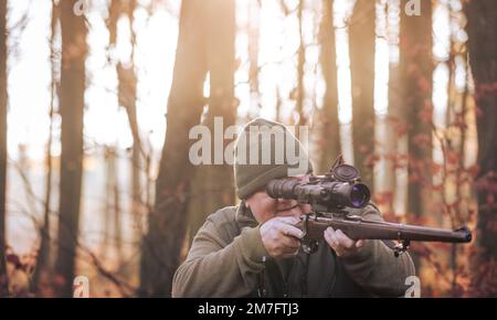 Saison de chasse d'automne, chasseur avec fusil à la recherche d'un animal sauvage dans un bois ou une forêt, concept de sports de plein air Banque D'Images