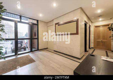 Hall d'entrée d'un immeuble résidentiel avec table pour le concierge, sols et murs en marbre et portes en chêne Banque D'Images