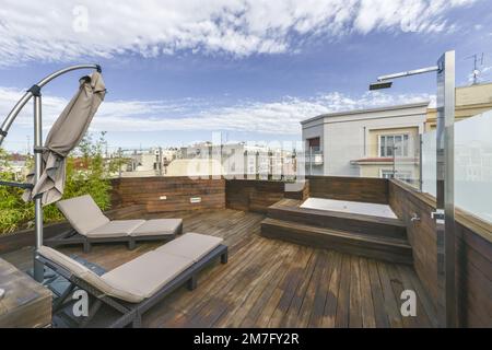 Terrasse dans la maison de grand standing, toutes couvertes de planches en bois d'acacia avec jacuzzi, douche en acier inoxydable et hamacs en rotin et vue sur la ville Banque D'Images