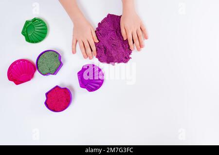 Sable cinétique coloré, moules en plastique pour sable. L'enfant sculpte et joue avec le sable. Vue de dessus. Arrière-plan blanc Banque D'Images