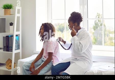 Une femme médecin écoute le dos de la patiente de la préadolescence pour vérifier ses poumons, sa respiration et son rythme cardiaque. Banque D'Images