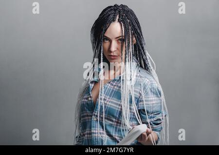 Portrait d'une femme avec une coiffure avec des dreadlocks sur fond gris Banque D'Images