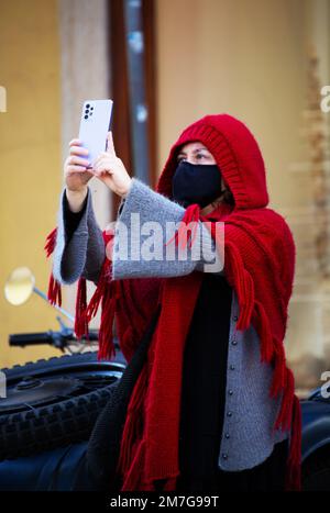 femme en vêtements d'hiver et masque de protection prend des photos du paysage avec son smartphone Banque D'Images