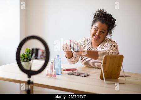 Blogueur de beauté avec produit de maquillage enregistrement vidéo sur smartphone Banque D'Images