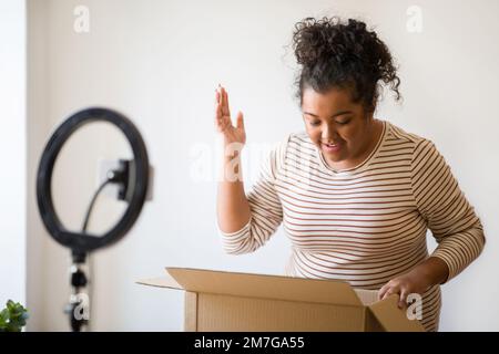 Excitée femme embonpoint célèbre blogger ouvrant paquet Banque D'Images