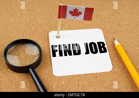 Sur la table se trouve le drapeau du Canada, un crayon, une loupe et une feuille de papier avec l'inscription - trouver un emploi. Banque D'Images