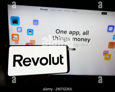 Personne tenant un smartphone avec le logo de la société britannique de fintech Revolut Ltd. À l'écran devant le site Web. Mise au point sur l'affichage du téléphone. Banque D'Images