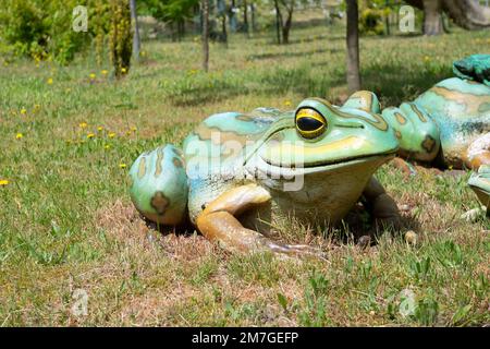 Grenouille en plastique factice et réaliste, assise dans l'herbe. Banque D'Images