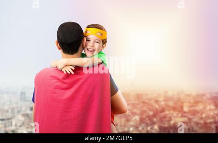 Mon adorable super père. Affectueux, un petit enfant câline le père avec amour, porte un masque orange, vêtu de costumes de super-héros, confiant dans la défense et le papa Banque D'Images