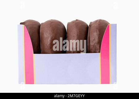 Quatre beignets au chocolat sucré dans une boîte en papier sur une table Banque D'Images