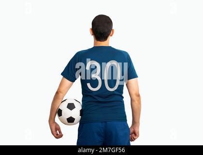 Image rognée et vue arrière d'un jeune joueur avec le numéro trente tenant un ballon de football sous ses bras avec un fond blanc Banque D'Images