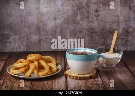 Chocolat chaud avec churos dans une tasse blanche et bleue, petit déjeuner typiquement espagnol sur une table en bois Banque D'Images