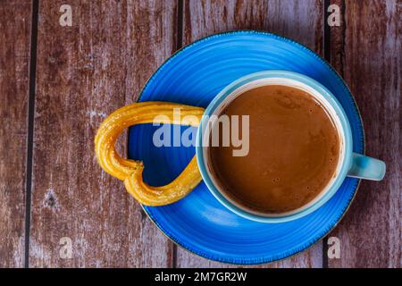 Chocolat chaud avec un churro sous forme de coeur sur une table en bois Banque D'Images