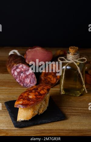 Tapa de chorizo ibérique sur du pain rustique avec de l'huile d'olive sur une ardoise noire avec fond noir Banque D'Images