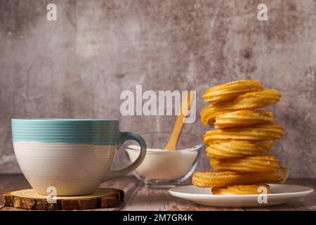 Chocolat chaud avec churos dans une tasse blanche et bleue, petit déjeuner typiquement espagnol sur une table en bois Banque D'Images