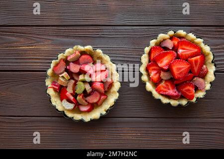 Délicieux tartes aux fraises et aux rhubarbe sur fond de bois brun, vue de dessus. Banque D'Images