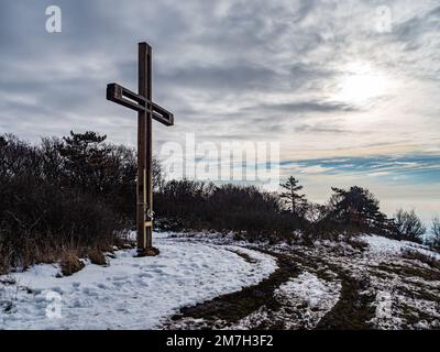 Croix en bois debout sur une montagne enneigée hiver ciel nuageux avec arbres solaires Banque D'Images