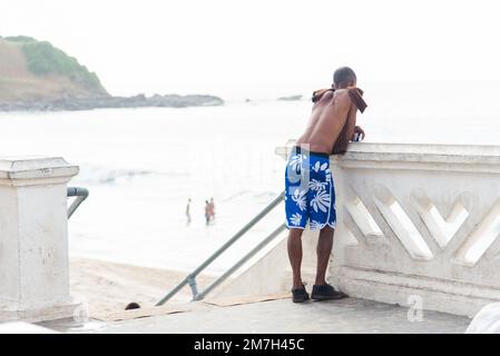 Salvador, Bahia, Brésil - 09 février 2018: L'homme regarde la mer depuis la plage de Farol da Barra après la nuit du carnaval à Salvador, Bahia. Banque D'Images