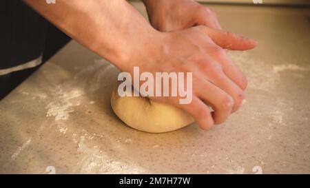les mains du maître pétrient la pâte de près. Cuisson à partir de farine de blé. Cuisiner à la maison. Banque D'Images