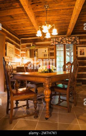 Vieille table à manger en bois et chaises dans la salle à manger à l'intérieur de 1987 maison en rondins de style chalet reconstruit. Banque D'Images