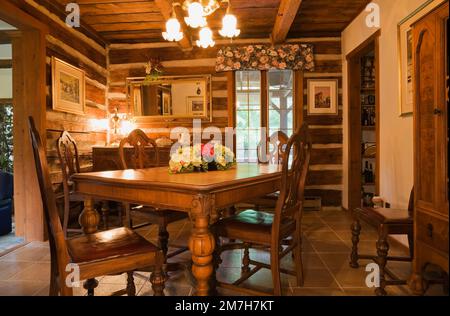 Vieille table à manger en bois et chaises dans la salle à manger à l'intérieur de 1987 maison en rondins de style chalet reconstruit. Banque D'Images