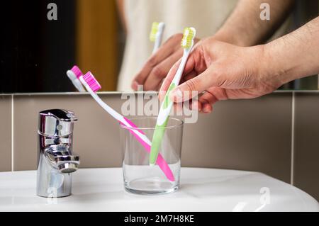 Gros plan d'un homme tenant une brosse à dents dans un support dans une salle de bains à la maison Banque D'Images
