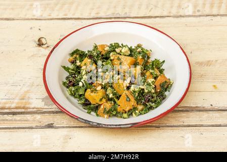 Une assiette avec une recette saine pour la salade de citrouille cuite avec des légumes verts de collard, des raisins secs et des pignons de pin frits Banque D'Images