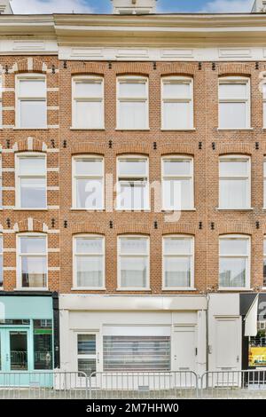 un bâtiment en brique avec de nombreuses fenêtres en haut et en bas, comme vu de l'autre côté de la rue il y a un bus garés devant Banque D'Images