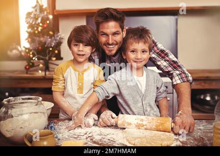 Faire cuire quelque chose de sucré pour maman. deux jeunes frères cuisant avec leur père dans la cuisine. Banque D'Images