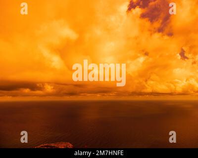 Vue aérienne coucher de soleil rouge sur la mer avec falaise volcanique rocheuse. Résumé nature été coucher de soleil océan mer fond. Petites vagues sur doré chaud Banque D'Images