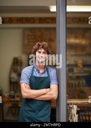 Fancy a coffee. A handsome young store owner standing in the entrance of his shop. Banque D'Images