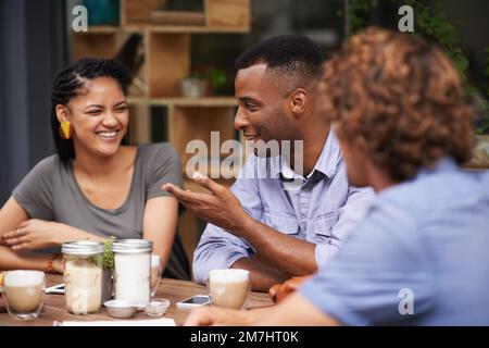 C'est le meilleur endroit de la ville. Un groupe de jeunes amis assis à l'extérieur dans un café-terrasse. Banque D'Images