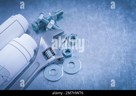 Vis à clé réglable, rondelles, écrous, boulons et rouleaux de dessins de construction sur fond métallique, vue de dessus, concept d'entretien. Banque D'Images