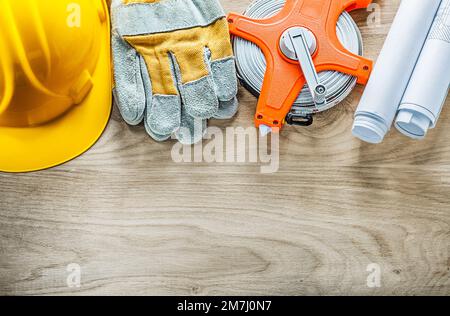 Bleu roulé gants de sécurité ruban mesure casque dur sur panneau en bois. Banque D'Images