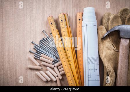 Tas de mètres en bois de chevilles bleus marteau gants de protection marron et clous métalliques sur le concept de construction de panneau de bois. Banque D'Images