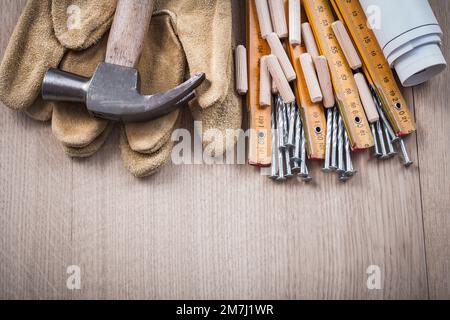Les goujons de mesure en bois Blueprints une paire de gants de protection et des clous métalliques sur le concept de construction de panneaux de bois. Banque D'Images