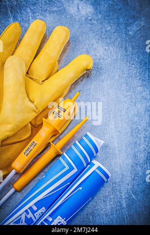 Gants de protection jaune pour testeur électrique bleus sur fond métallique. Banque D'Images