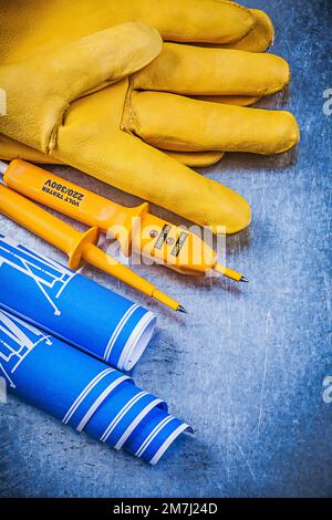 Gants de sécurité jaune pour testeur électrique bleus roulés sur fond métallique. Banque D'Images