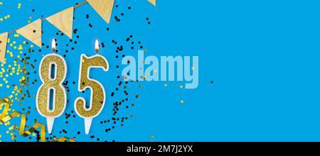 Bougie d'or numéro quatre-vingt-cinq. Carte d'anniversaire avec inscription 85 sur fond bleu. Célébration d'anniversaire. Bannière. Banque D'Images